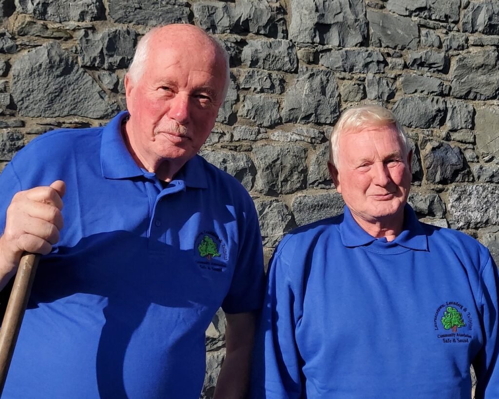 Photo of two men who volunteer for the LLTCA Safe and Sound Handyman Service. Both are wearing branding clothing, blue with the LLTCA tree logo.