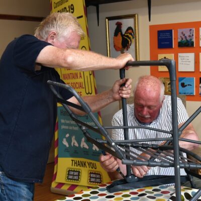 Photo of two volunteers fixing a chair.